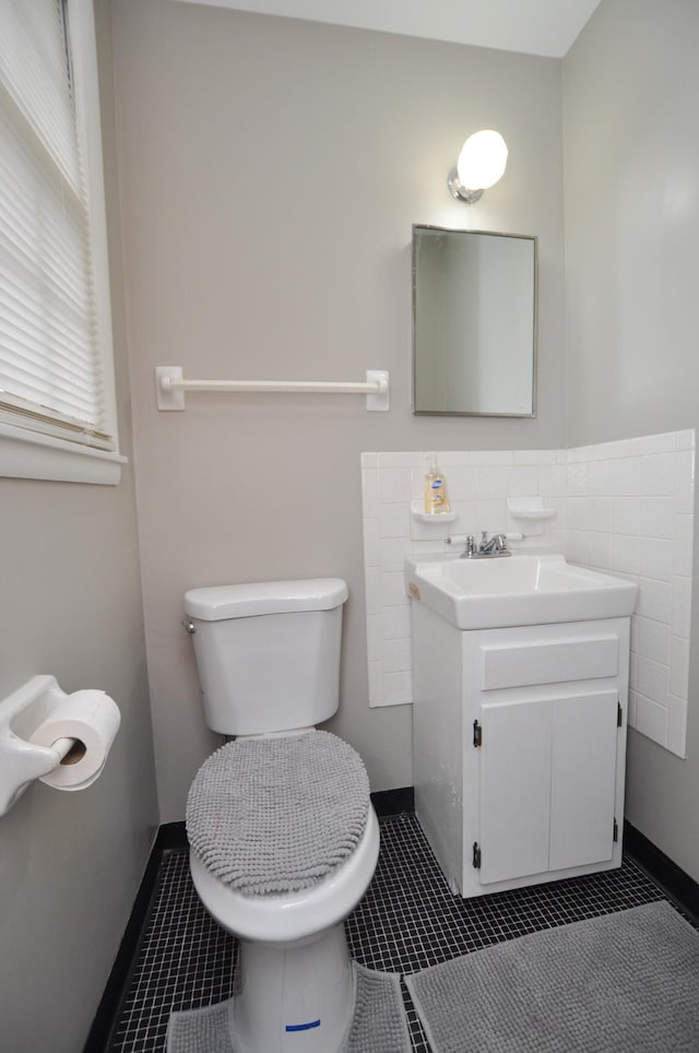 bathroom featuring tile patterned floors, vanity, tile walls, and toilet