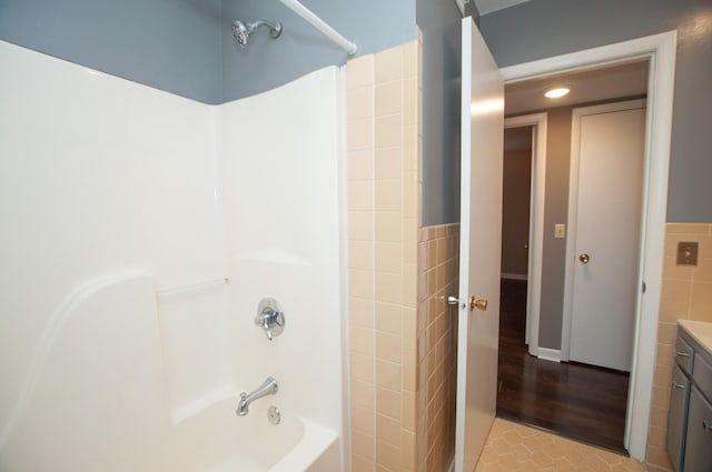 bathroom featuring tile patterned floors, vanity, shower / bath combination, and tile walls