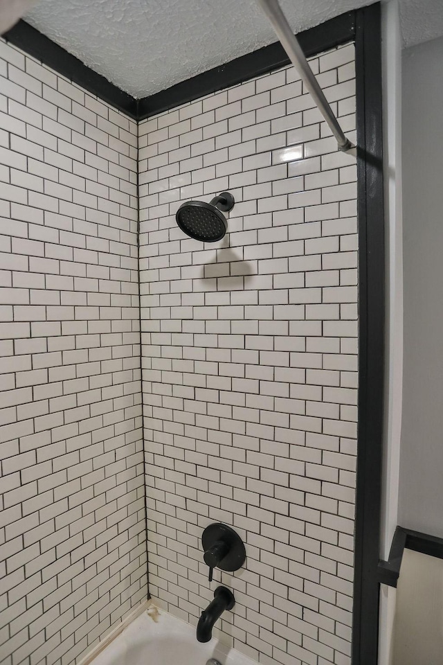 bathroom featuring washtub / shower combination and a textured ceiling