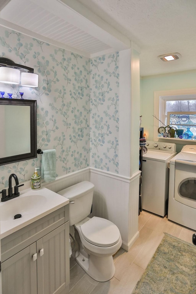 bathroom featuring washer and clothes dryer, vanity, and toilet