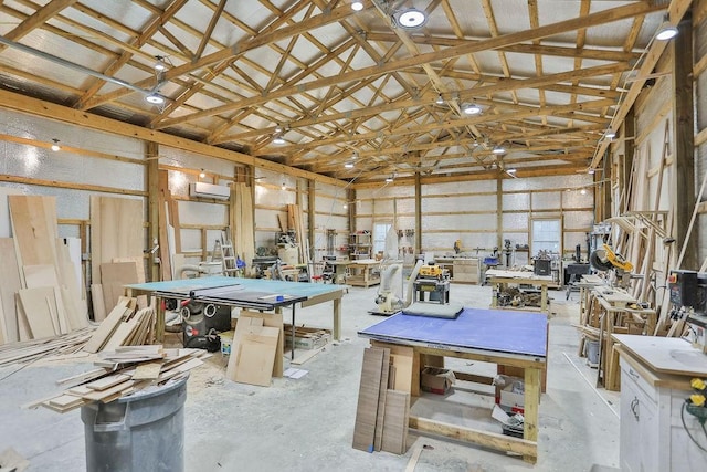 interior space featuring high vaulted ceiling, concrete flooring, a workshop area, and an AC wall unit