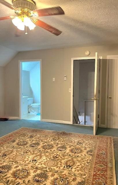 interior space featuring lofted ceiling, ensuite bath, ceiling fan, a textured ceiling, and carpet floors