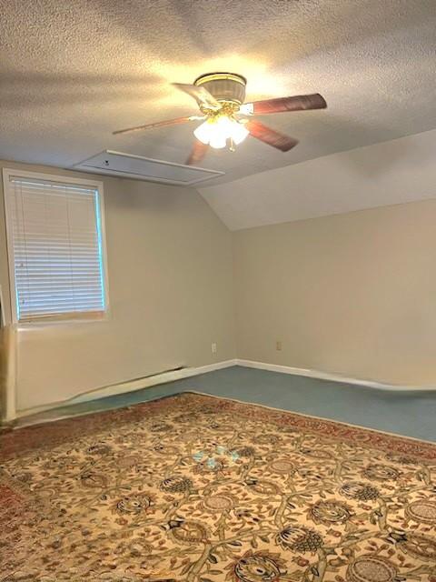 empty room with a textured ceiling, vaulted ceiling, and ceiling fan