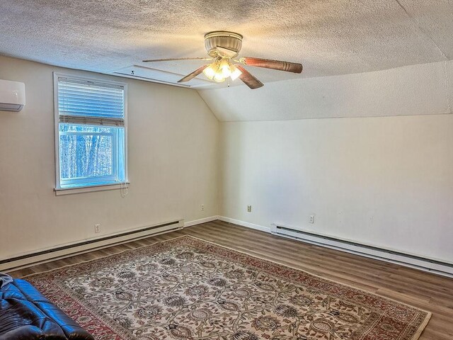 additional living space with a wall mounted air conditioner, baseboard heating, and wood finished floors