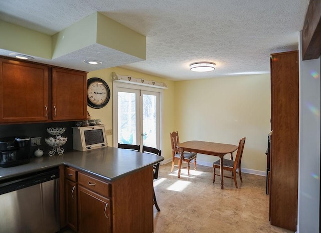 kitchen with dishwasher, a textured ceiling, dark countertops, and baseboards