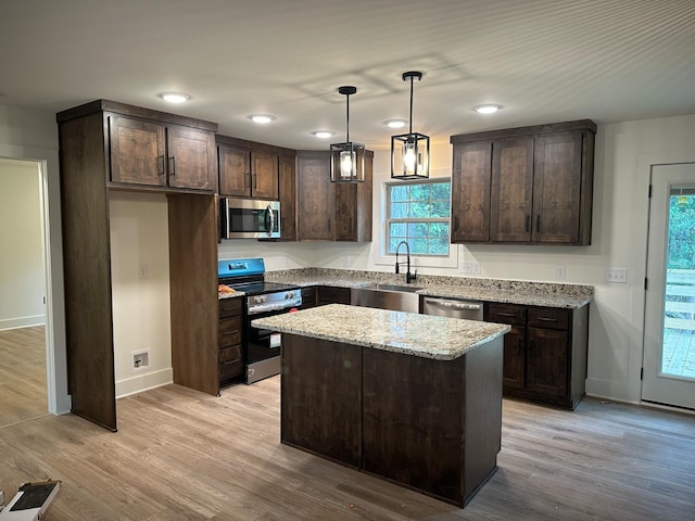 kitchen with a center island, sink, appliances with stainless steel finishes, and light hardwood / wood-style flooring