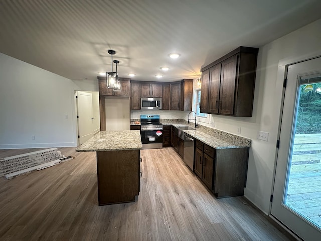 kitchen featuring light hardwood / wood-style floors, a kitchen island, hanging light fixtures, and appliances with stainless steel finishes