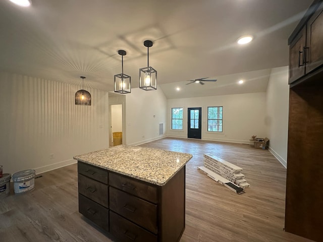 kitchen featuring dark brown cabinets, ceiling fan, dark wood-type flooring, pendant lighting, and a kitchen island