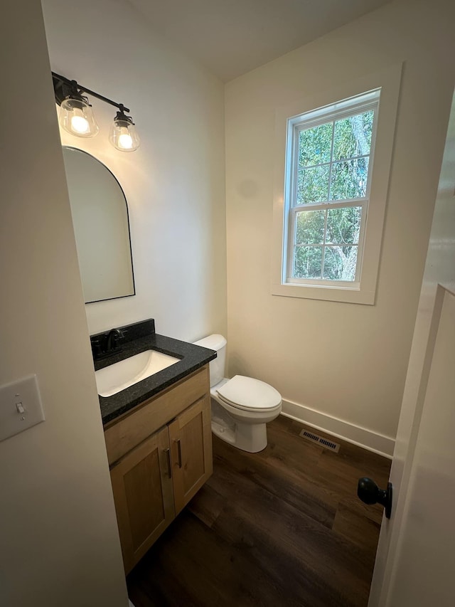 bathroom with toilet, vanity, and hardwood / wood-style flooring