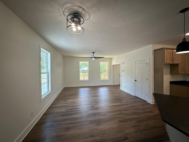 unfurnished living room with a textured ceiling, ceiling fan, and dark wood-type flooring