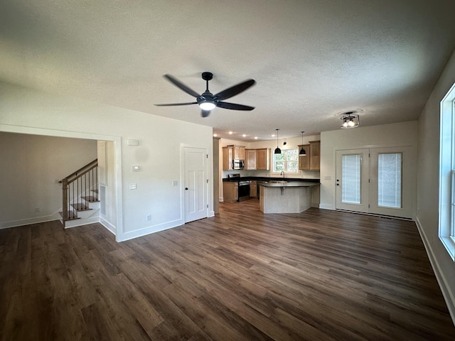 unfurnished living room featuring a textured ceiling, ceiling fan, dark wood-type flooring, and sink