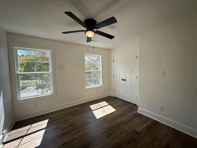 unfurnished bedroom with multiple windows, ceiling fan, a closet, and dark hardwood / wood-style floors