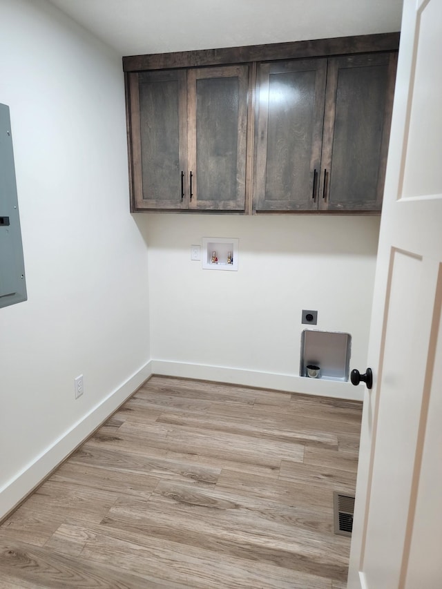 laundry room with cabinets, electric dryer hookup, electric panel, hookup for a washing machine, and light hardwood / wood-style floors