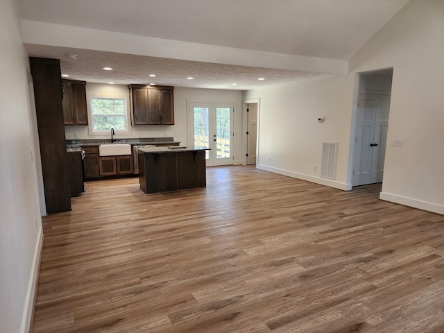 kitchen with french doors, dark brown cabinets, sink, light hardwood / wood-style flooring, and a center island