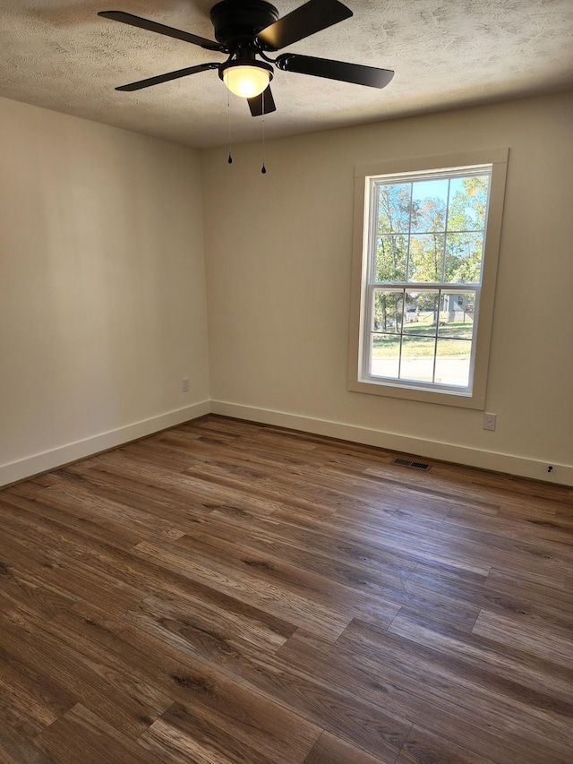 unfurnished room with ceiling fan, dark hardwood / wood-style flooring, and a textured ceiling