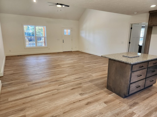 interior space featuring light stone countertops, light wood-type flooring, dark brown cabinets, vaulted ceiling, and ceiling fan