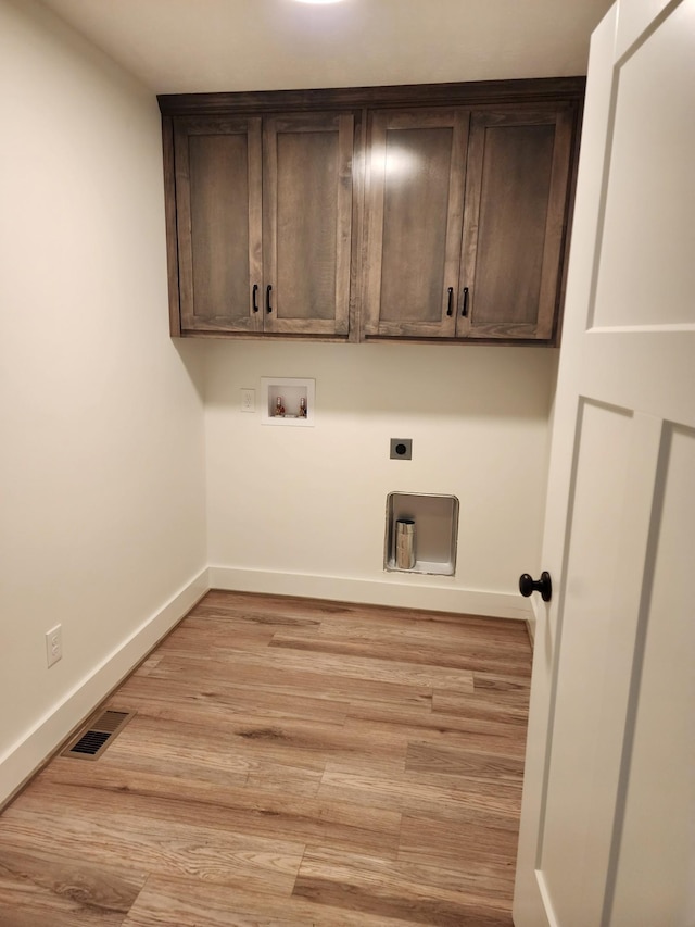 clothes washing area featuring cabinets, light wood-type flooring, washer hookup, and hookup for an electric dryer