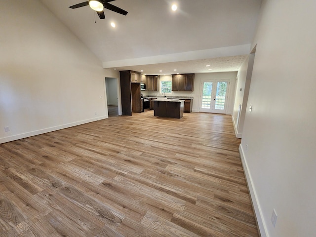 unfurnished living room with ceiling fan, french doors, sink, high vaulted ceiling, and light wood-type flooring