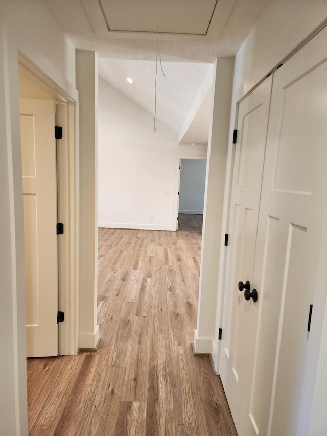 hall with light hardwood / wood-style floors and lofted ceiling