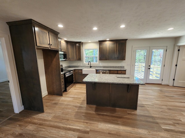 kitchen with a healthy amount of sunlight, a center island, light hardwood / wood-style floors, and appliances with stainless steel finishes