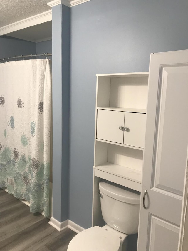 bathroom featuring wood-type flooring, toilet, curtained shower, and crown molding