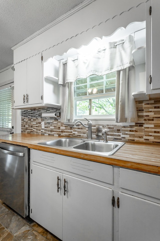 kitchen with backsplash, stainless steel dishwasher, a textured ceiling, sink, and white cabinets