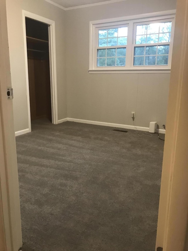 unfurnished bedroom featuring dark colored carpet, a walk in closet, and a closet