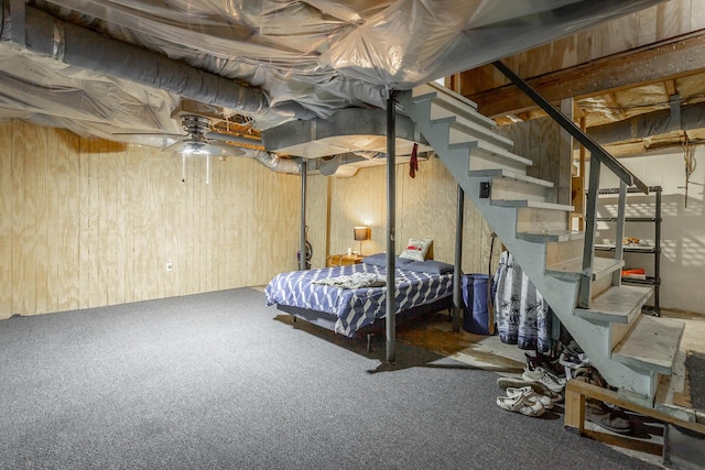 unfurnished bedroom featuring carpet flooring, ceiling fan, and wooden walls