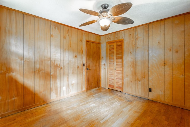 empty room featuring wooden walls, hardwood / wood-style floors, and ceiling fan