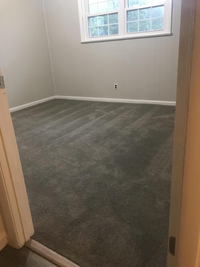 empty room with dark colored carpet and plenty of natural light