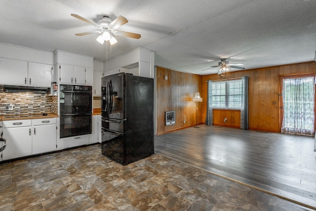 kitchen with heating unit, white cabinetry, wooden walls, and black appliances