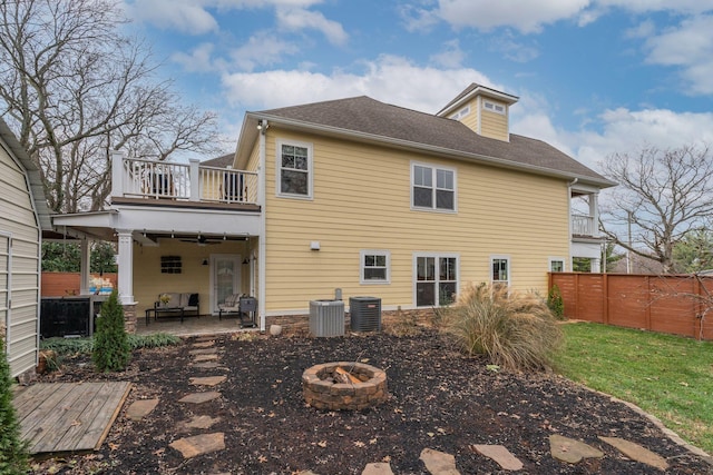 rear view of house with cooling unit, a balcony, an outdoor fire pit, and a patio