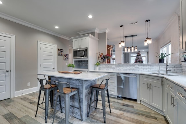 kitchen featuring appliances with stainless steel finishes, light wood-type flooring, a kitchen breakfast bar, sink, and a kitchen island