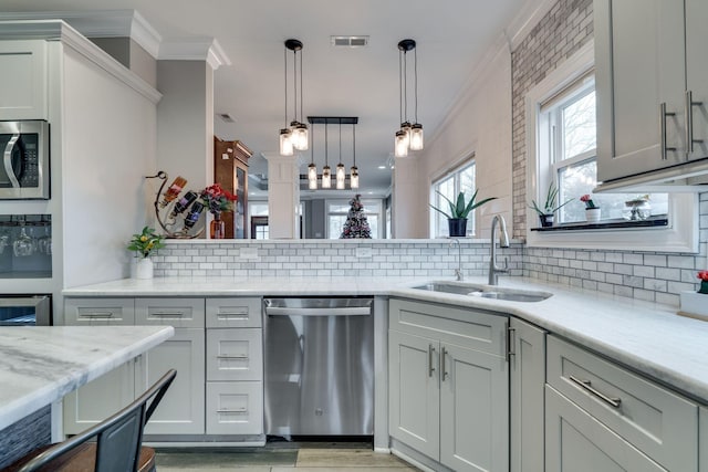 kitchen with light stone countertops, sink, stainless steel appliances, tasteful backsplash, and pendant lighting