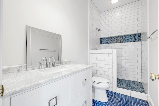 bathroom featuring vanity, tile patterned flooring, toilet, and tiled shower