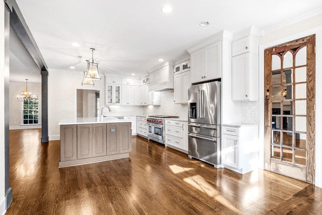 kitchen with dark wood-type flooring, high quality appliances, an island with sink, pendant lighting, and white cabinets