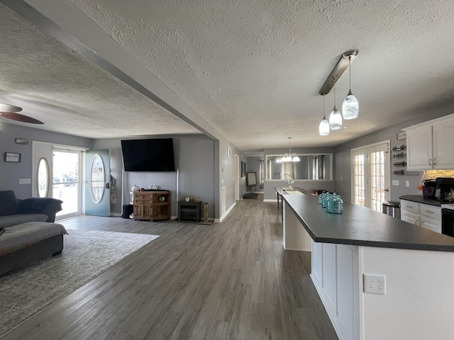 kitchen featuring dark wood-type flooring, dark countertops, open floor plan, and white cabinetry