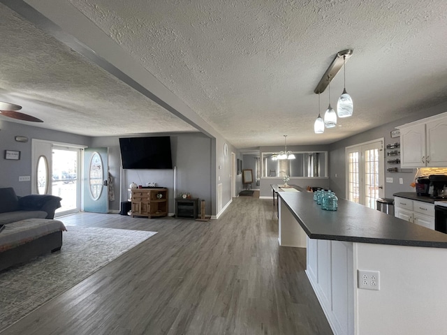 173 Twin Oaks Dr, Hohenwald, TN 38462 - kitchen with dark countertops, open floor plan, a textured ceiling, white cabinets, and a center island