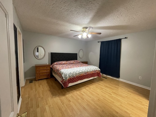 bedroom featuring a ceiling fan, light wood-style flooring, baseboards, and a textured ceiling