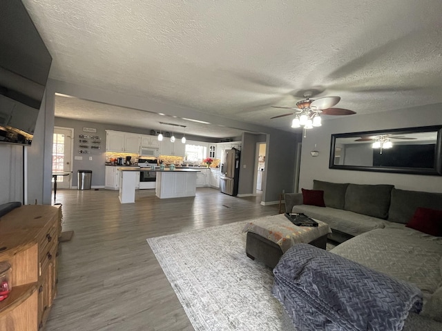 living room featuring a textured ceiling, light wood-type flooring, and a ceiling fan