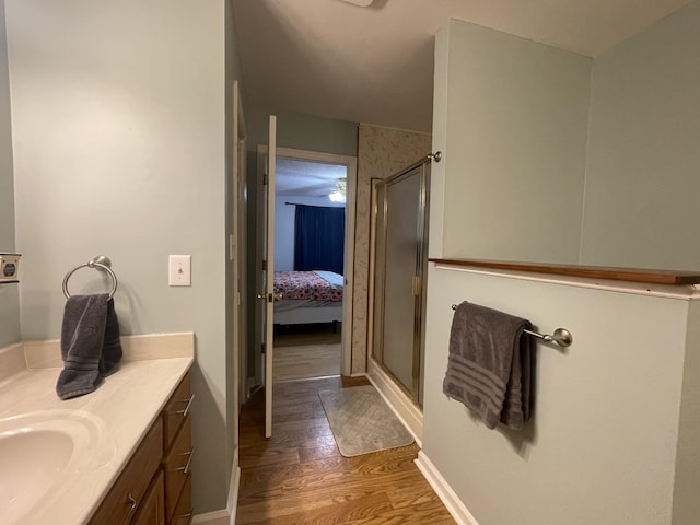 ensuite bathroom with baseboards, wood finished floors, ensuite bathroom, vanity, and a shower stall