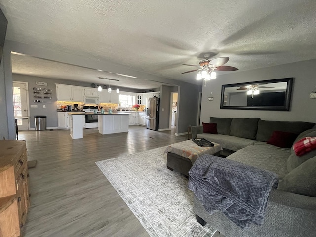 living area with a textured ceiling, a ceiling fan, and wood finished floors