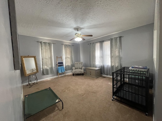 sitting room with carpet floors, a textured ceiling, baseboards, and a ceiling fan