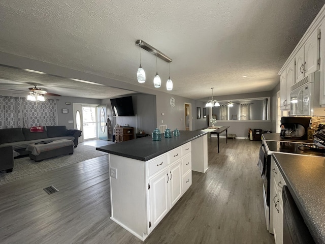 kitchen featuring white microwave, open floor plan, electric stove, a center island, and dark countertops