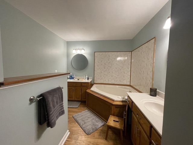 full bath featuring a sink, two vanities, a bath, and wood finished floors