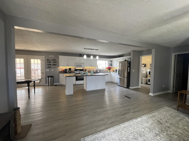 kitchen featuring a center island, range with electric stovetop, dark wood-type flooring, white cabinetry, and stainless steel fridge with ice dispenser