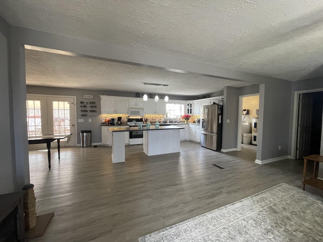 173 Twin Oaks Dr, Hohenwald, TN 38462 - kitchen with white appliances, a textured ceiling, white cabinetry, a center island, and dark wood-style flooring