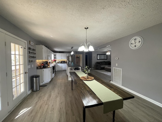 dining room with visible vents, a textured ceiling, baseboards, and wood finished floors