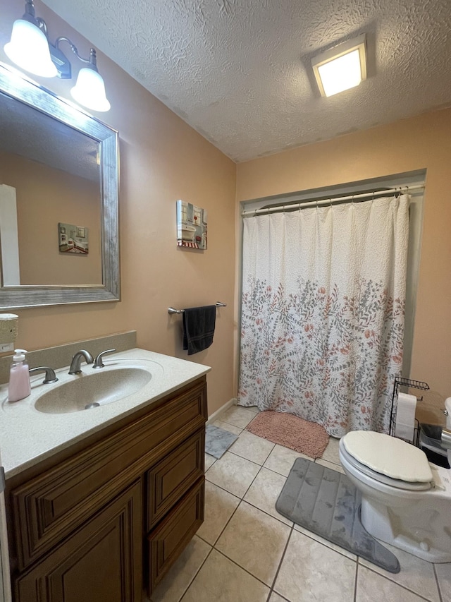 bathroom featuring tile patterned flooring, vanity, toilet, and a textured ceiling