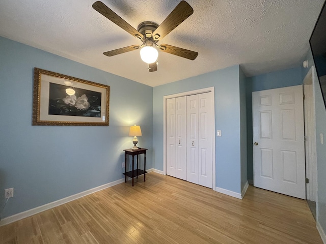 unfurnished bedroom with a closet, light wood-style flooring, baseboards, and a textured ceiling